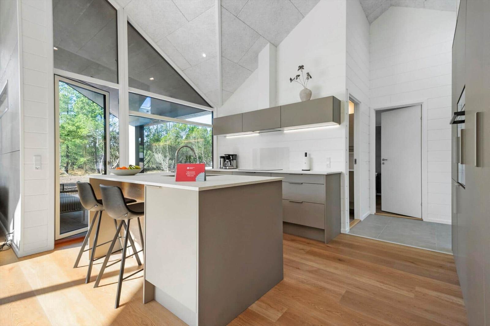 Modern kitchen with island, bar stools, and view of the garden.