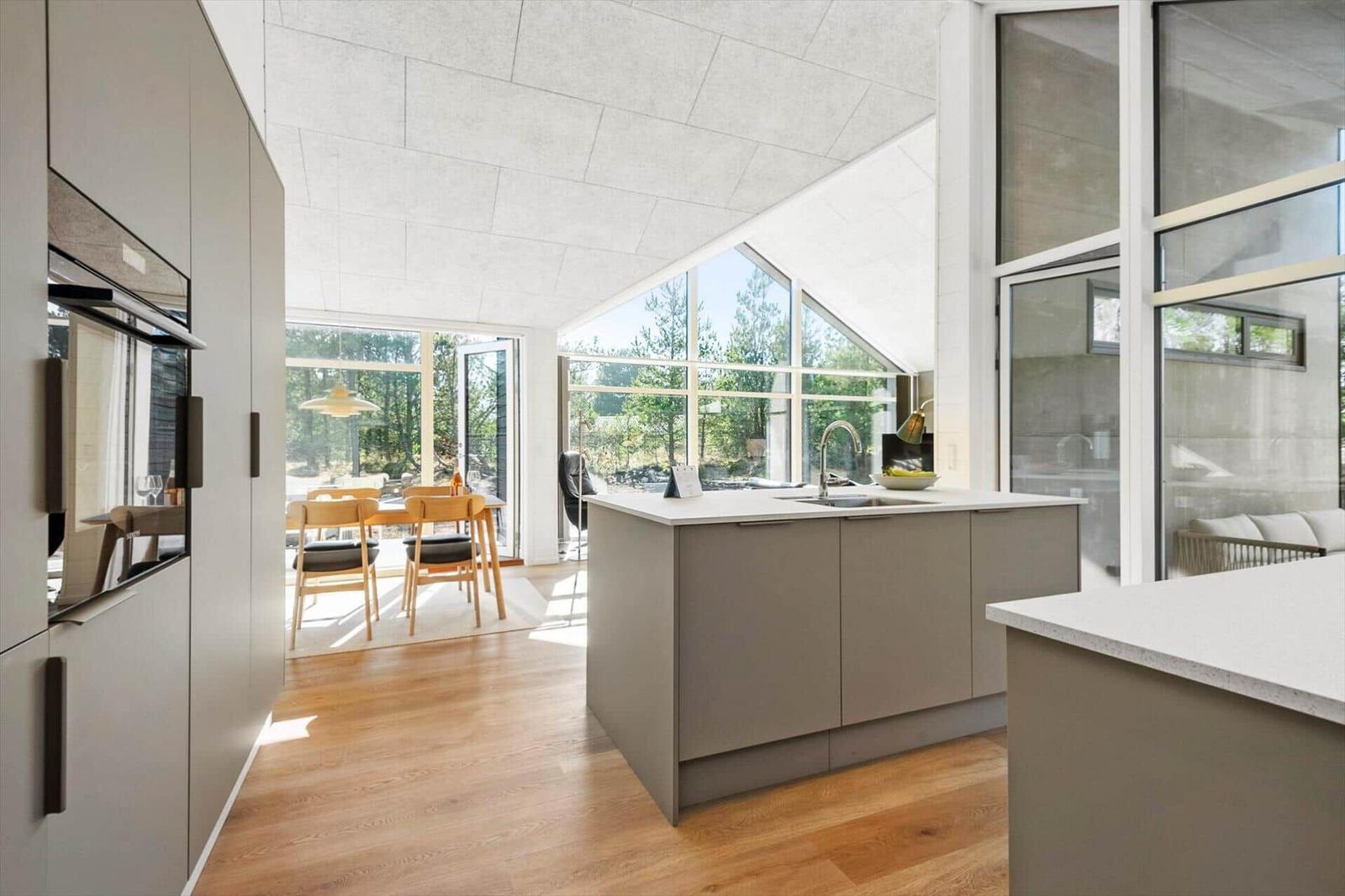 Modern kitchen with island, hardwood floor, and large windows for views.