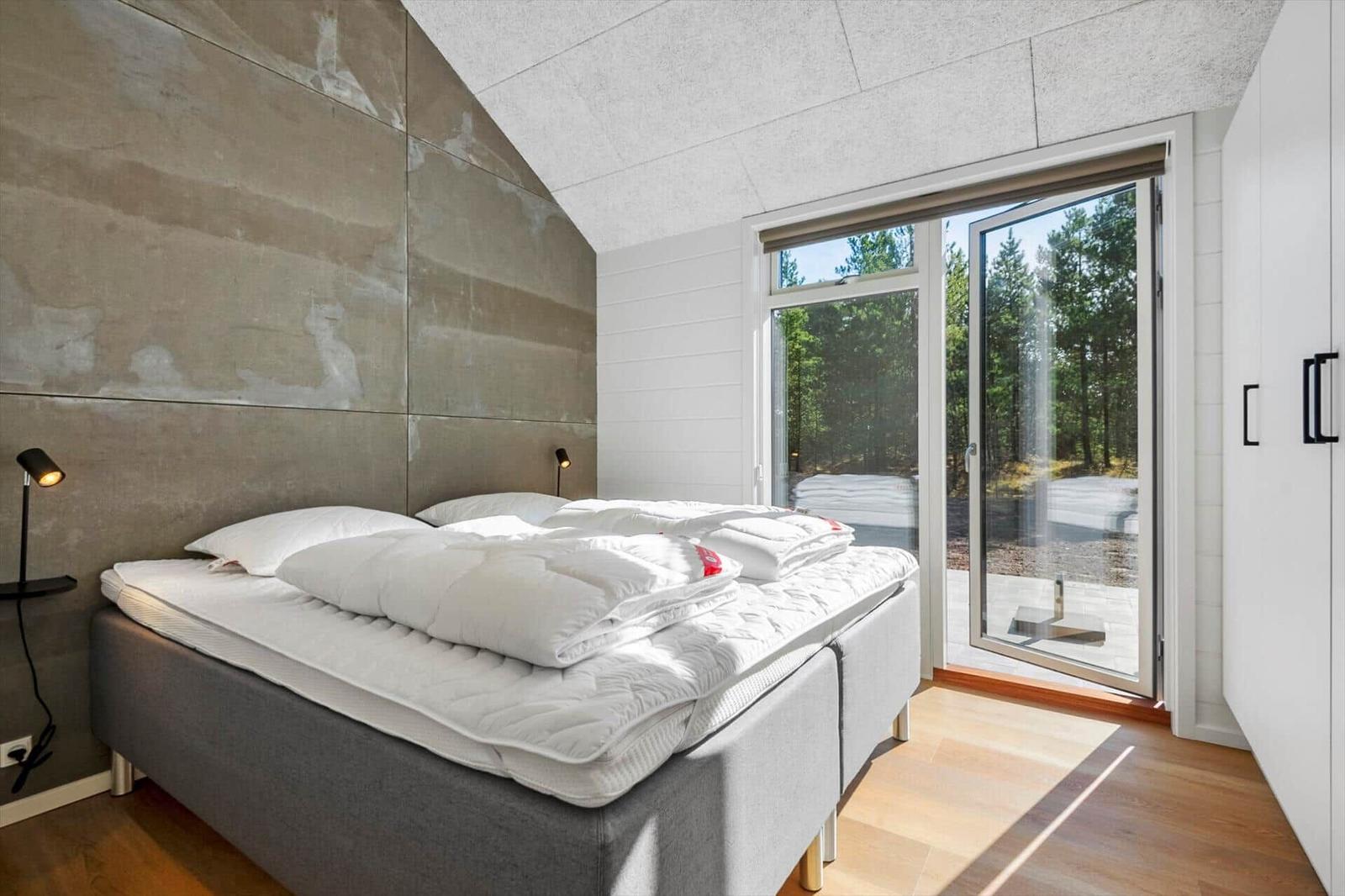 Bedroom with bed, window and wooden floor.