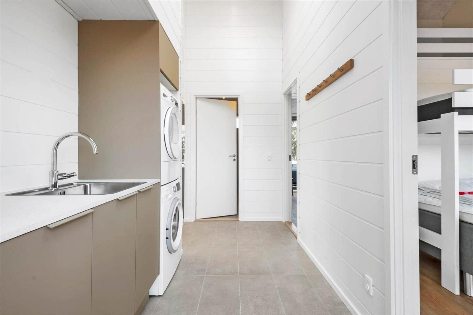 Kitchen with sink and washing machine. View into bedroom with loft bed.