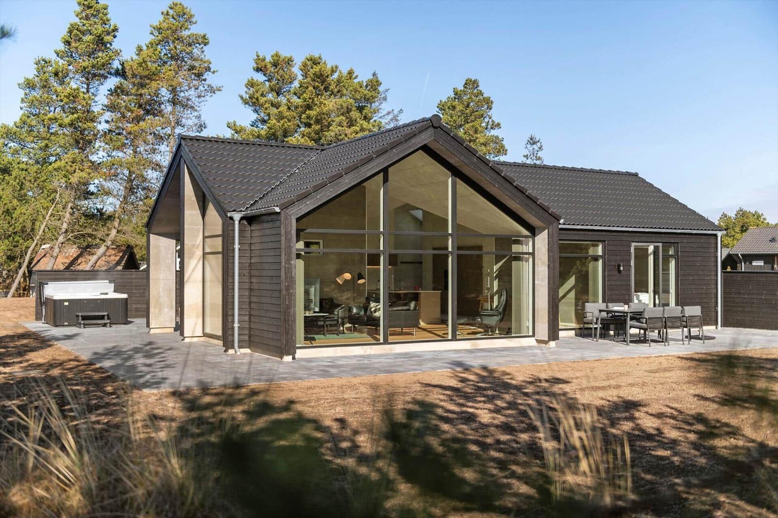 Modern house with large glass area and outdoor terrace with seating.