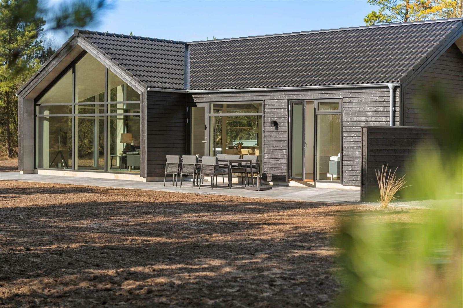 Modern wooden house with large glass area and terrace in the woods