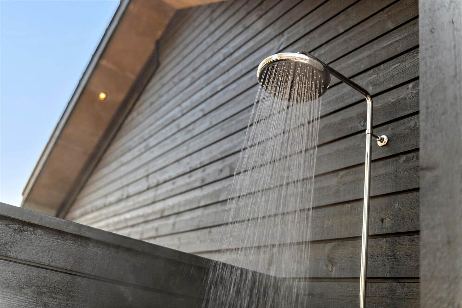 Outdoor shower with water stream against wooden wall