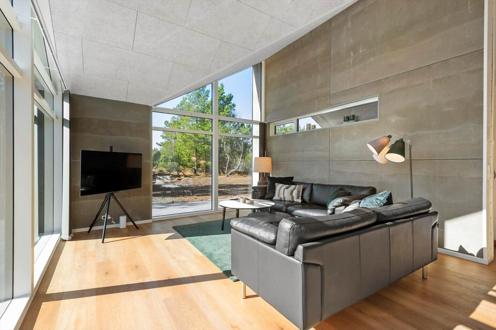 Living room with large sofa, TV, and panoramic windows to the outside.