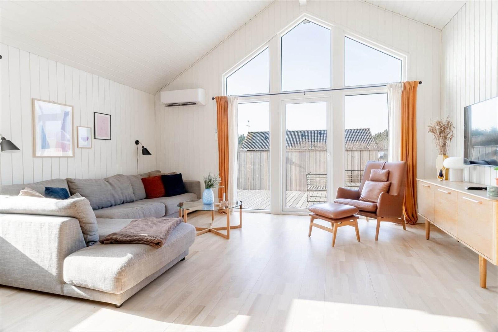 Wohnzimmer mit Sofa, Sessel und großem Fenster zur Terrasse.