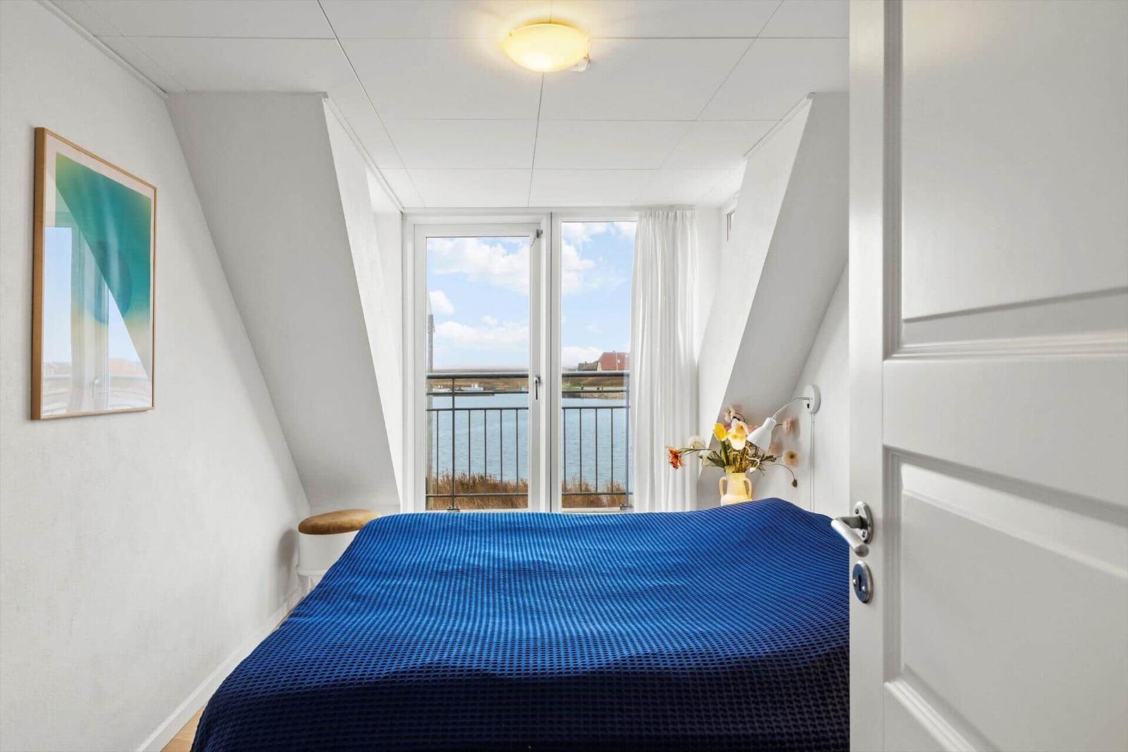 Schlafzimmer mit Balkonblick auf Wasser und Himmel
