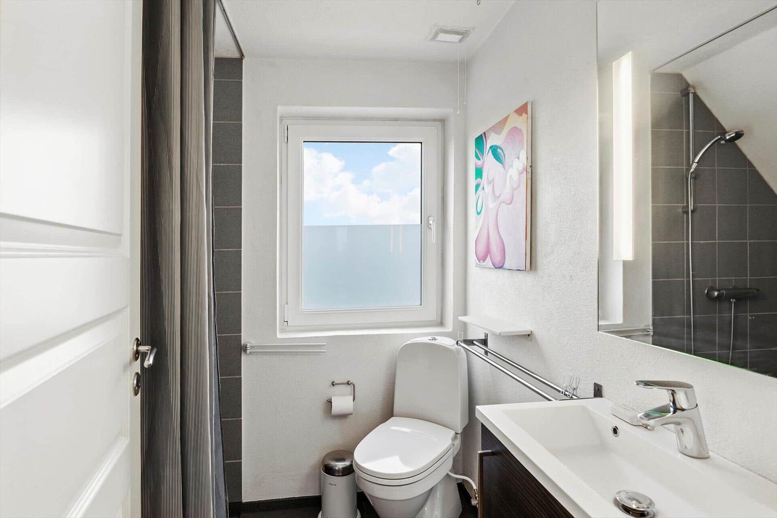 Badezimmer mit Toilette, Waschbecken und Dusche. Fenster mit Meerblick.