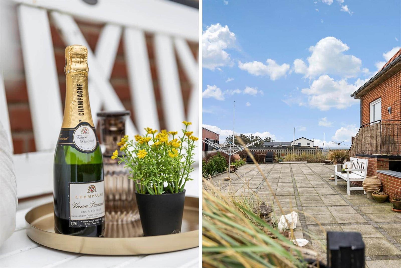 Champagnerflasche und Pflanze auf Tisch. Terrasse mit Sitzgelegenheit und Blick auf Himmel.