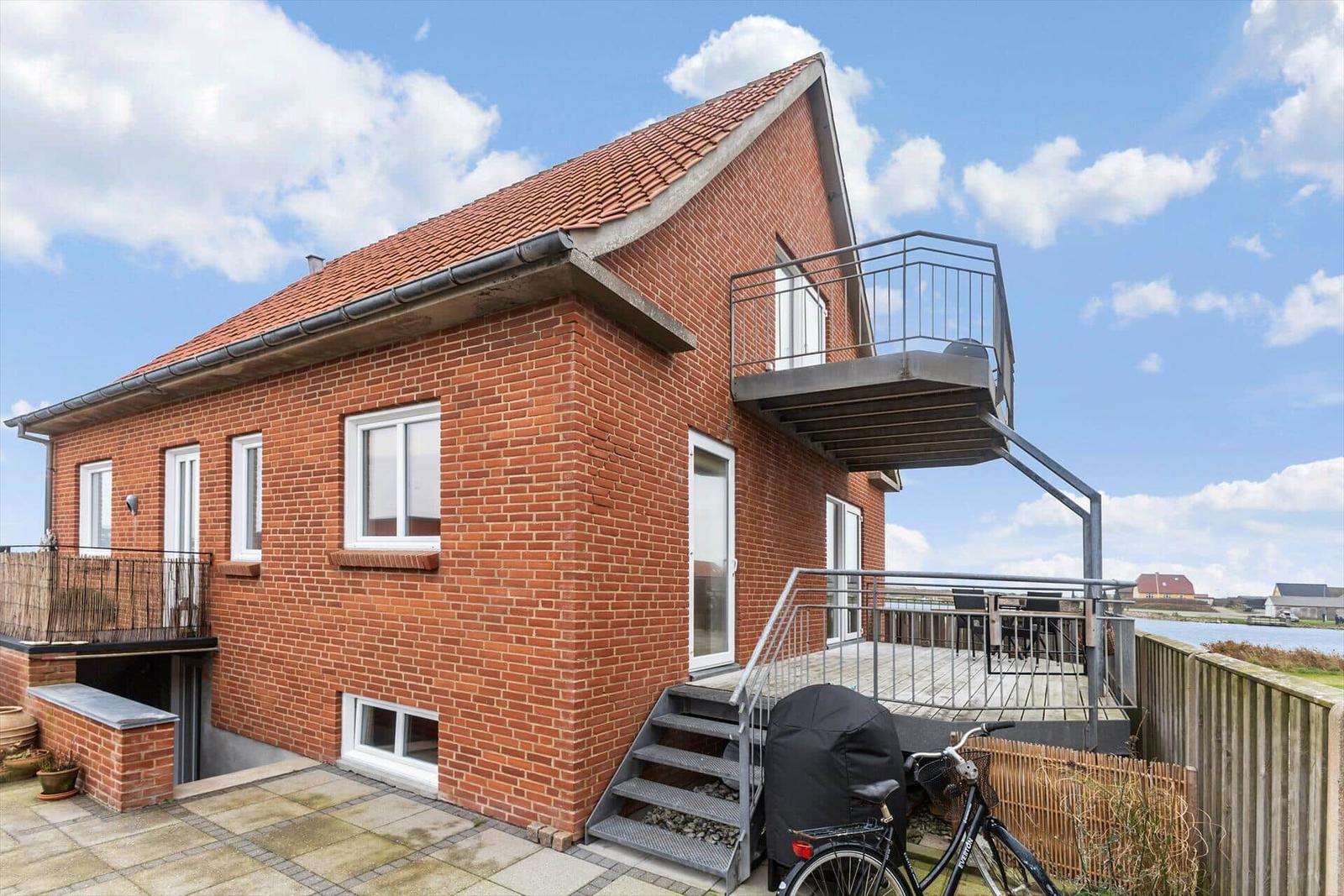 Rotes Backsteinhaus mit Balkon und Terrasse an Wasser