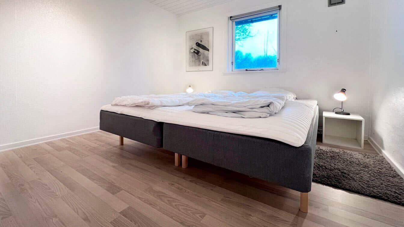 Schlafzimmer mit Bett, Nachttisch und Fenster.