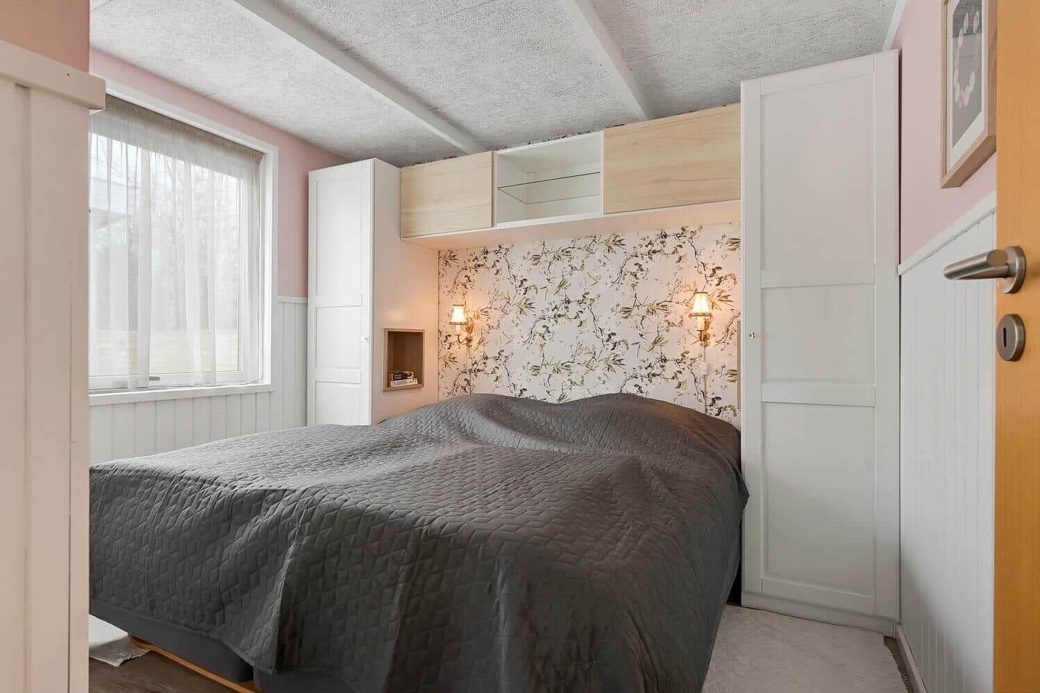 Schlafzimmer mit Bett, Wandverkleidung und integriertem Schrank.