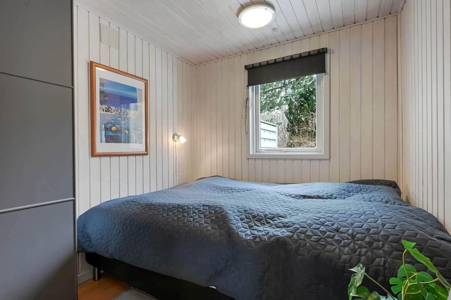 Schlafzimmer mit Bett, Fenster und Wandbild.