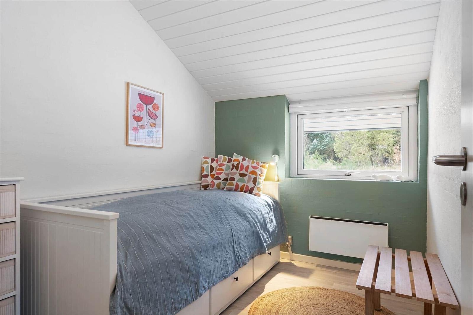 Schlafzimmer mit Bett, Fenster und Holzbank.