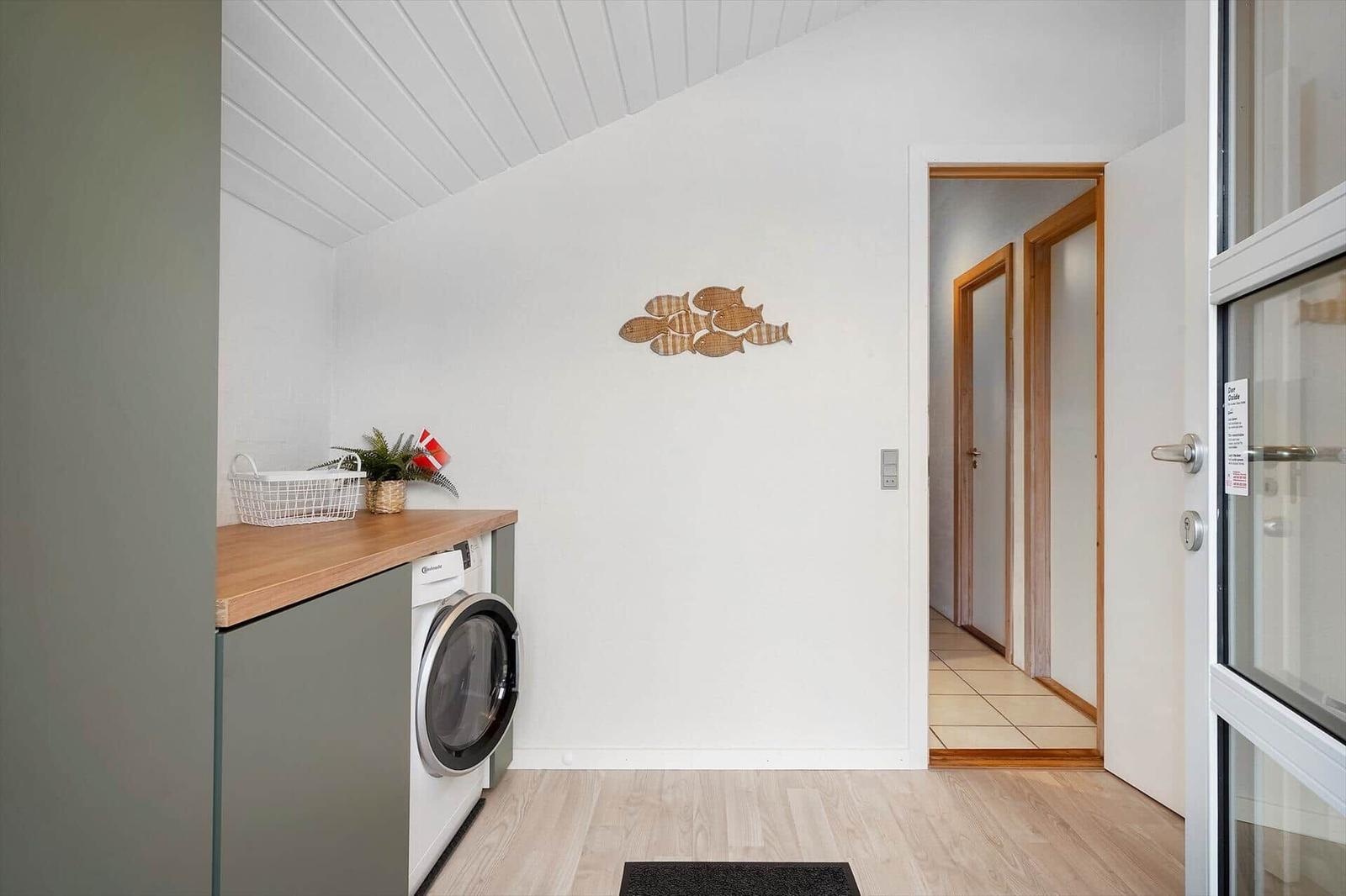 Waschmaschine mit Holzoberfläche und Fischdekoration an der Wand.