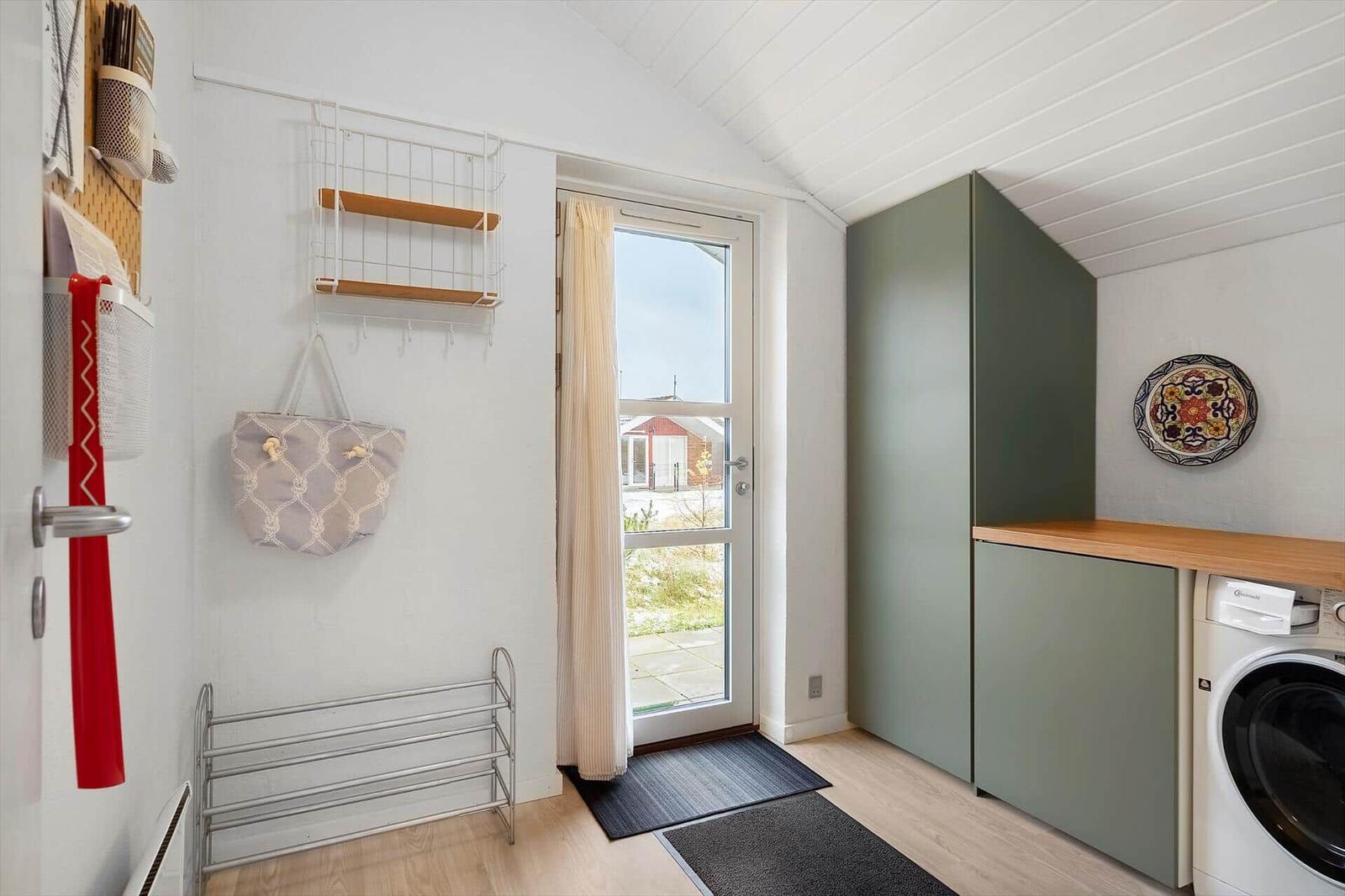 Eingangsbereich mit Waschmaschine, Garderobe und Tür zum Garten.