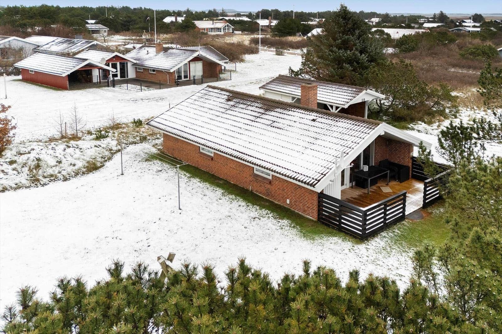 Ein Haus mit Schnee bedecktem Dach und Terrasse im Winter.