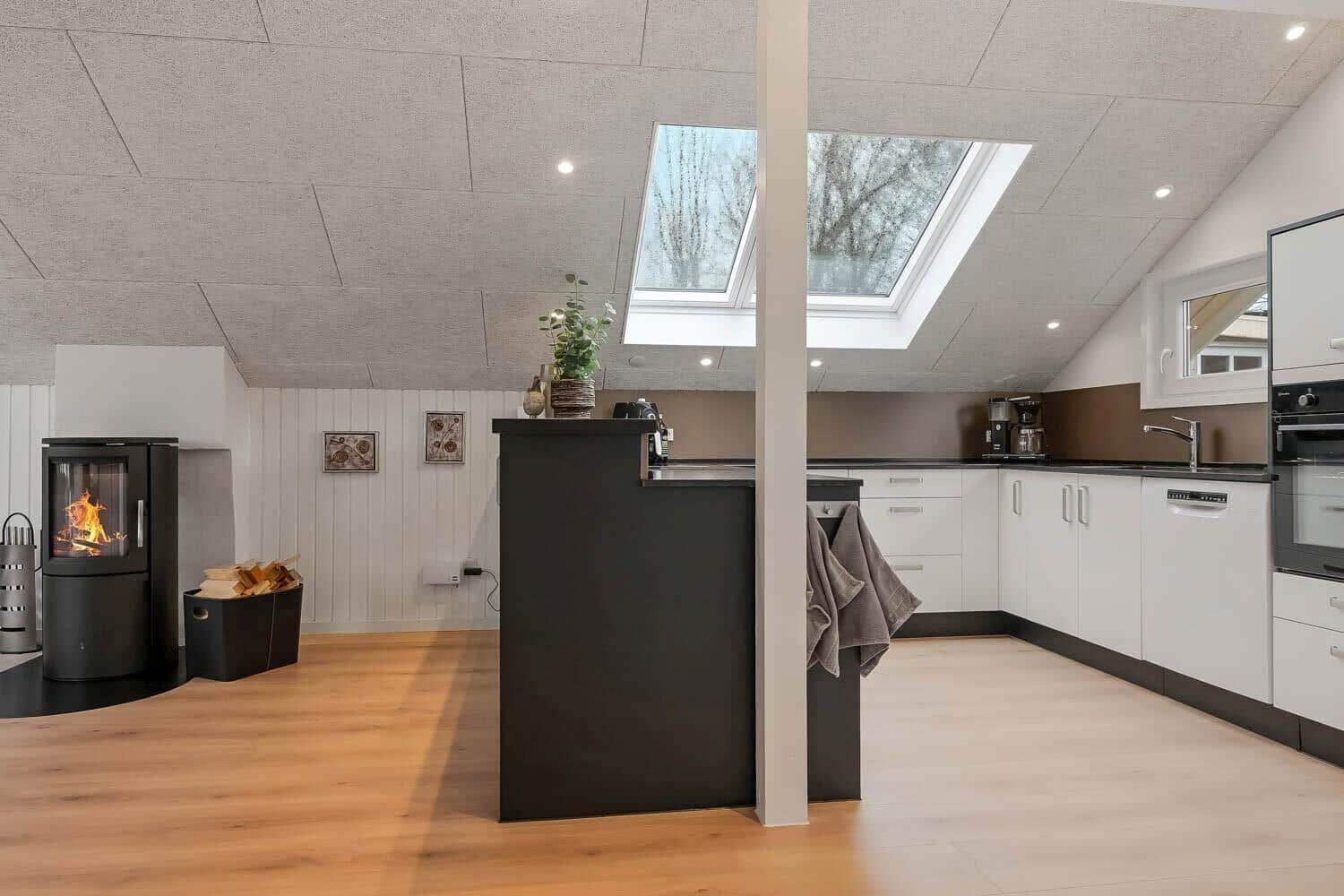 Küche mit Esstisch, Holzboden und Dachfenster. Kaminofen und moderne Geräte.