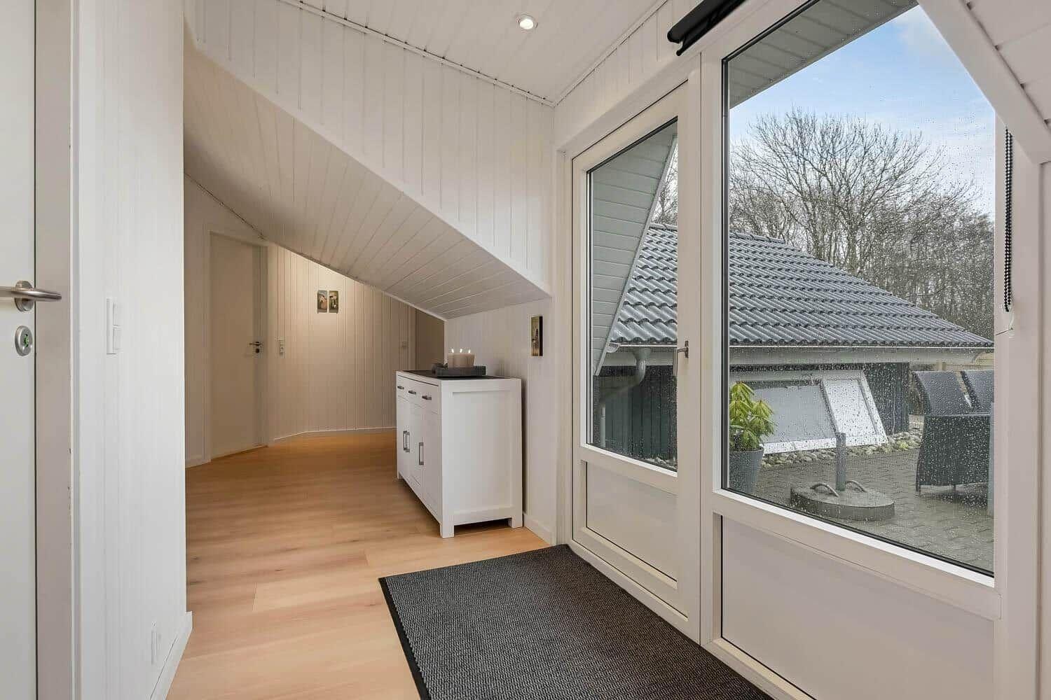Eingangsbereich mit Holzboden und großem Fenster zur Terrasse.