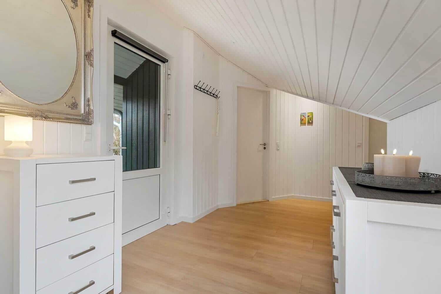 Wohnbereich mit weißen Schränken, Holzboden und Spiegelschrank