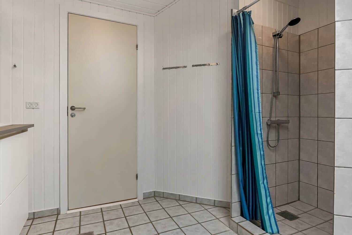 Badezimmer mit Dusche, blauer Vorhang und weißer Tür.