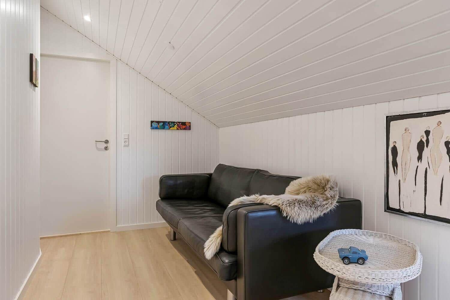 Schwarzes Sofa mit Felldecke, weißer Wandschrank und Bild an der Wand.