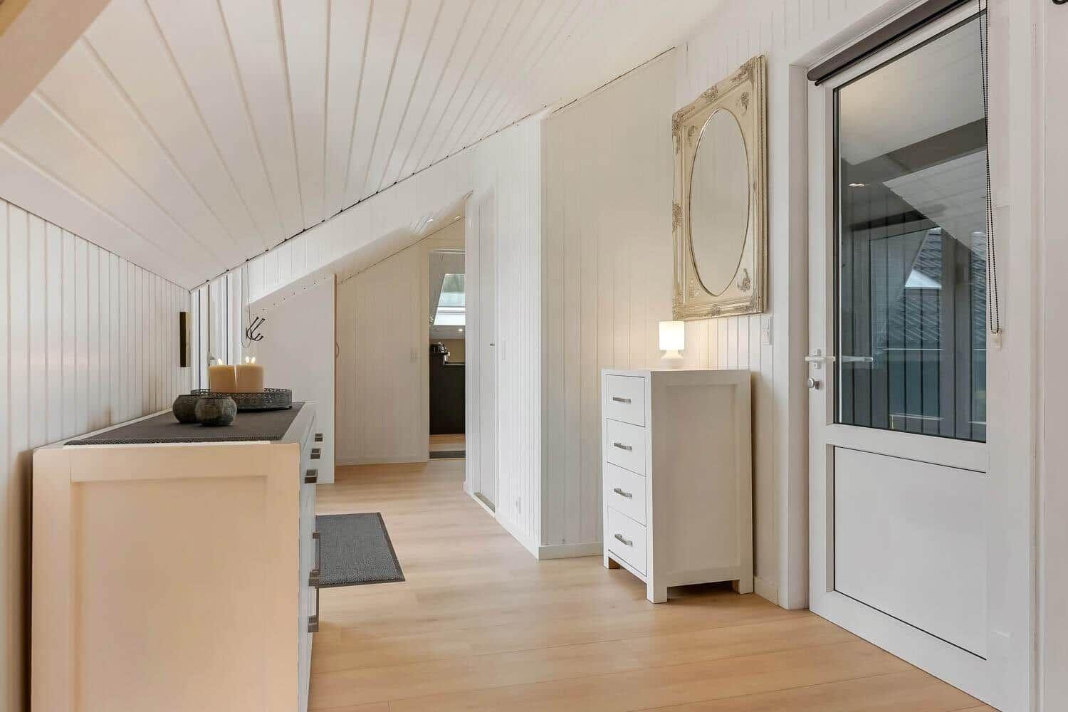 Flur mit weißem Schrank, Spiegel und Glastür. Holzboden und weiße Wände.