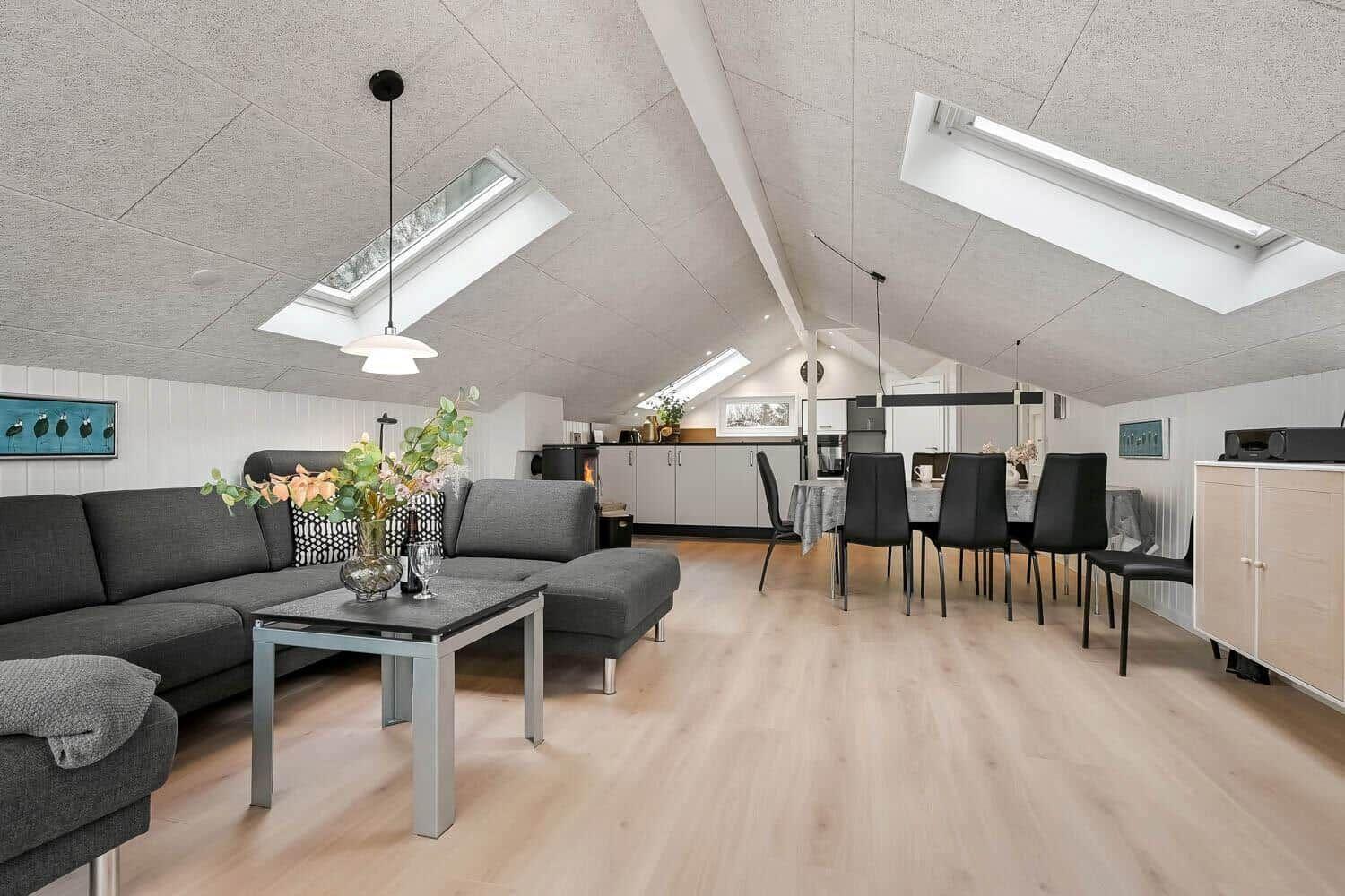 Wohn- und Essbereich mit Sofa, Esstisch und Küchenzeile unter Dachschrägen.