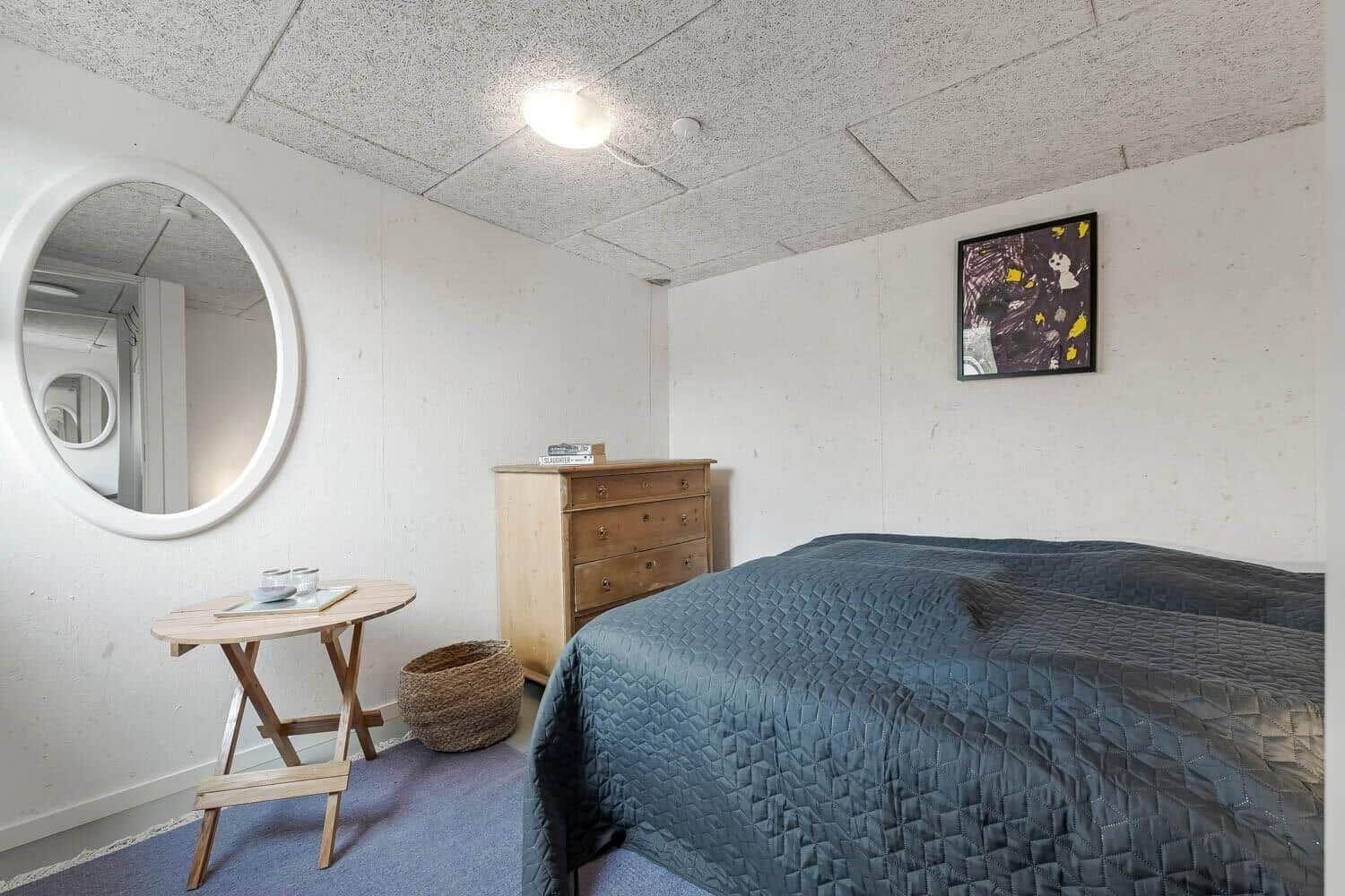 Schlafzimmer mit Bett, Schrank, runden Spiegel und Tisch.