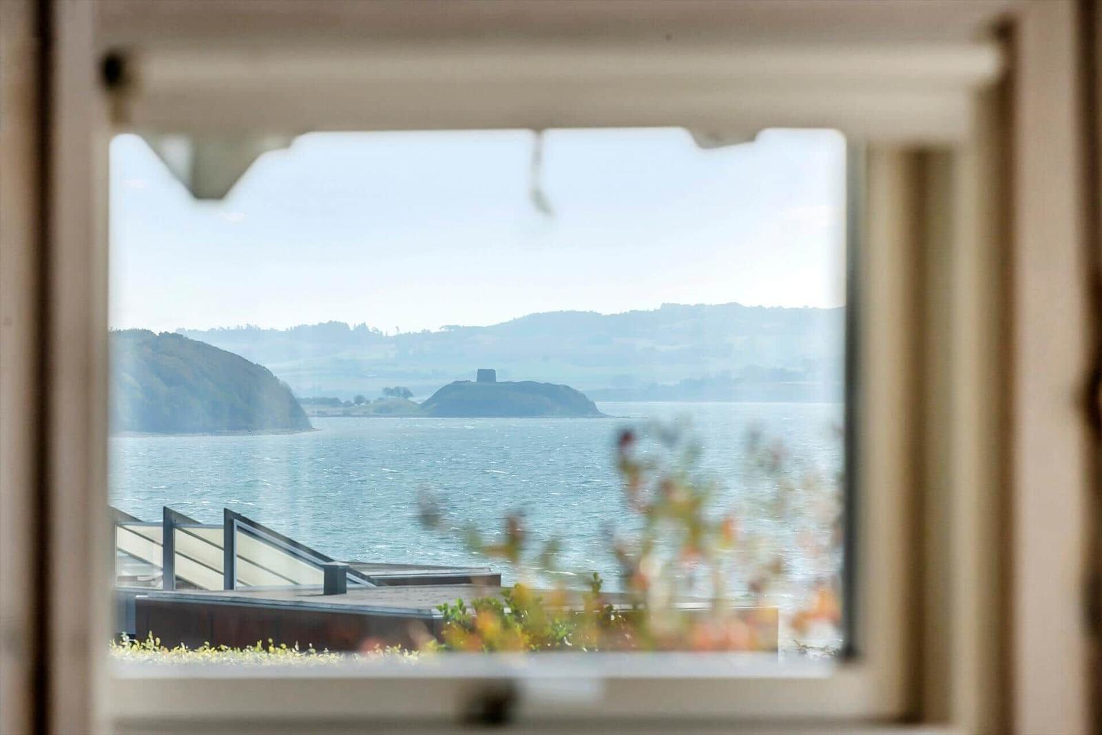 View through a window to a lake with islands and hills in the background.
