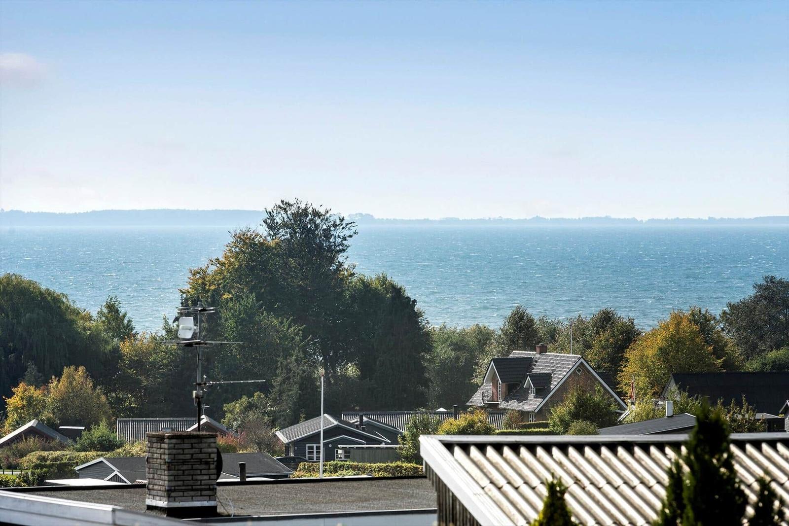 View of the sea with trees and houses in the foreground.