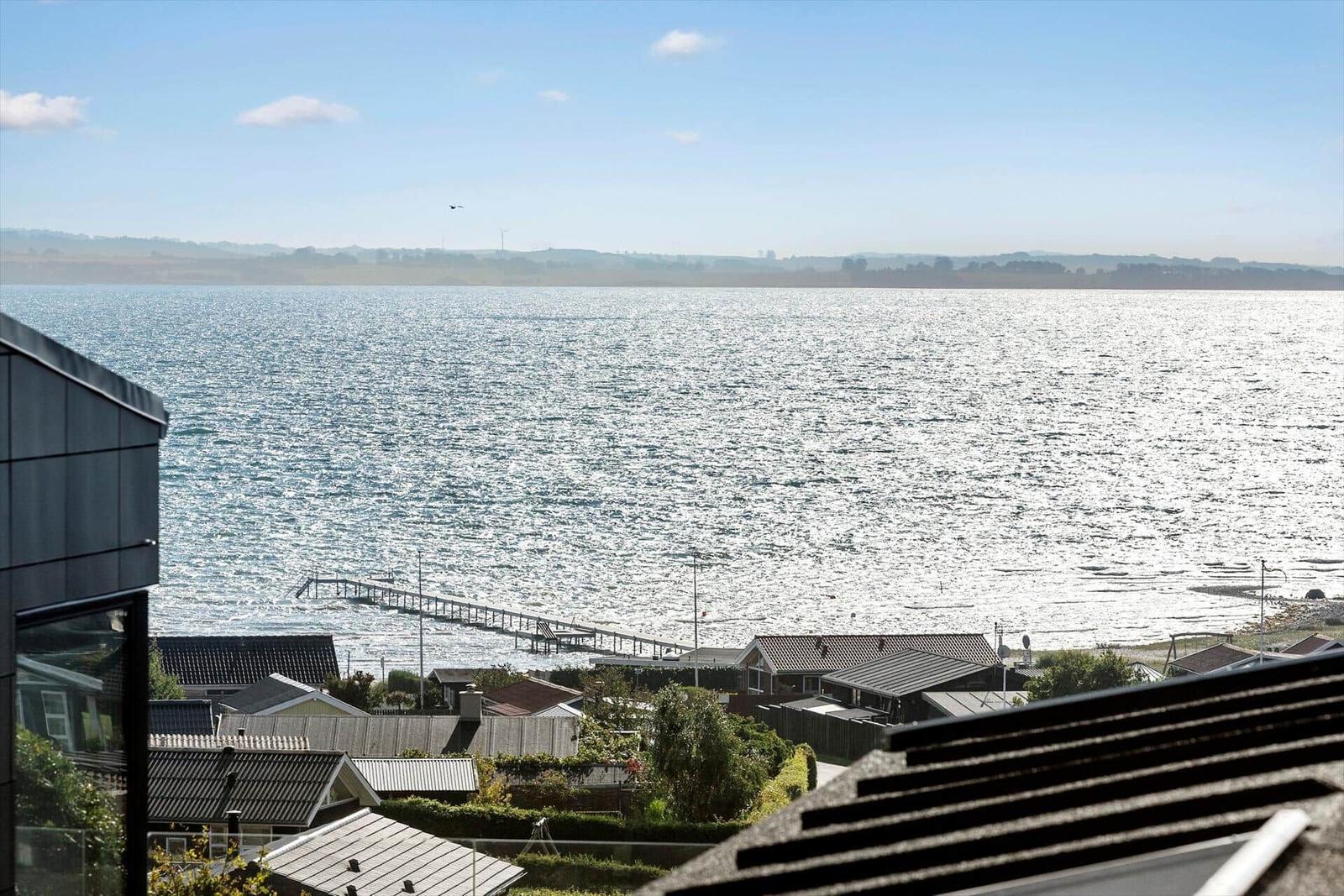 Panoramic view of the sea with a pier and houses in the foreground.