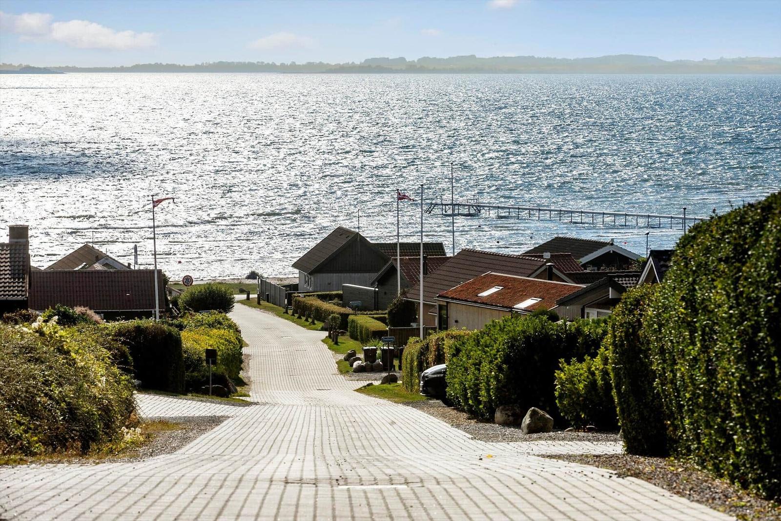 Path leads to houses by water with view of a harbor.