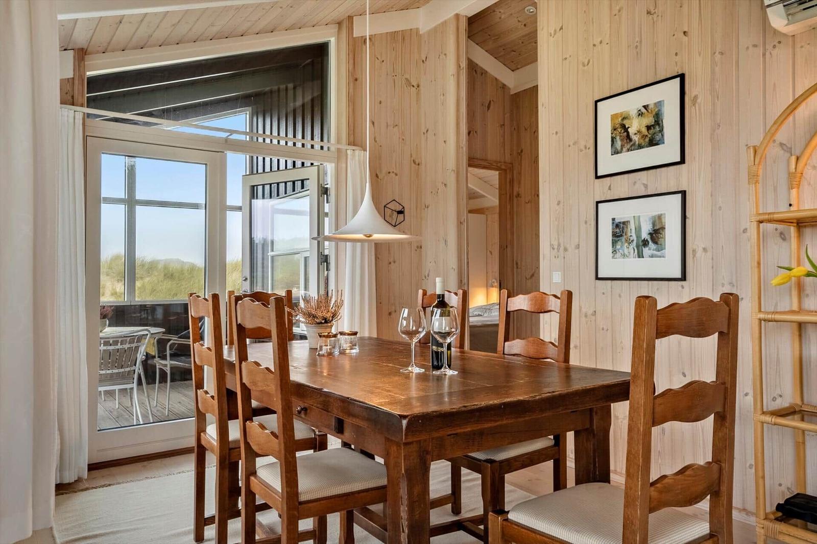 Esszimmer mit Holztisch, Stühlen und Blick auf Terrasse.