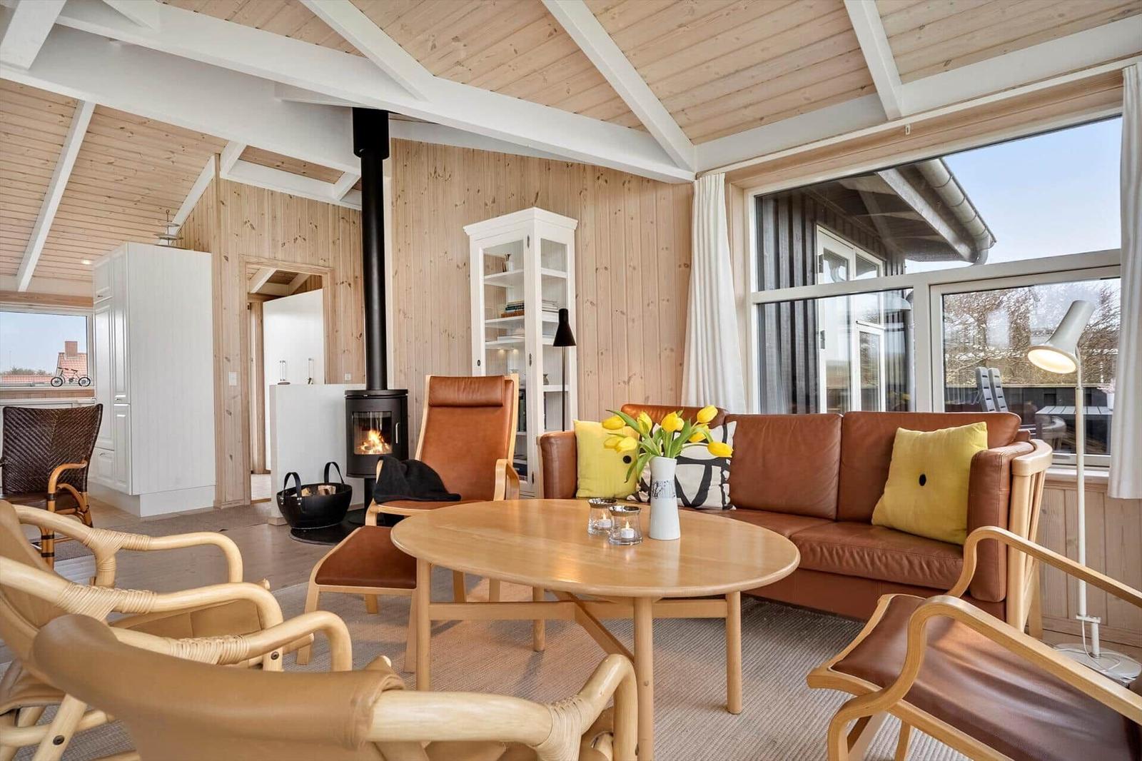 Wohnzimmer mit Holzwand, Sofa, Kamin und großem Fenster.