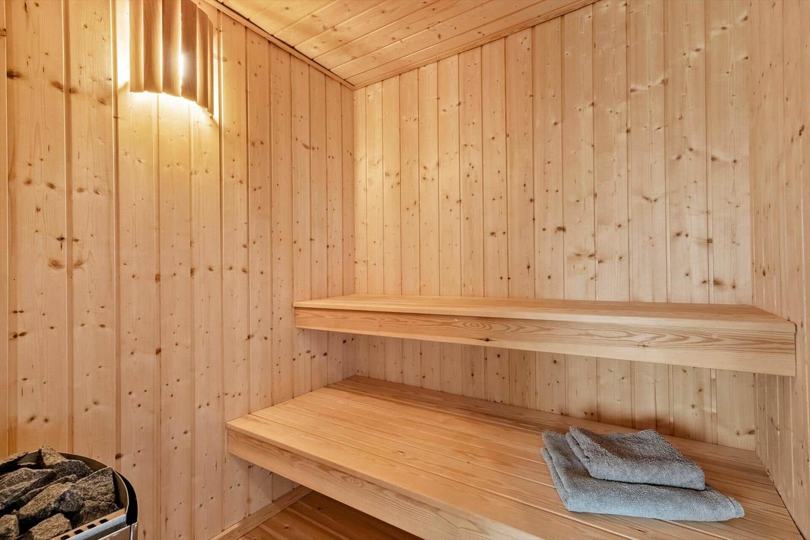 Sauna mit Holzwand, Sitzbänken und Handtuch.