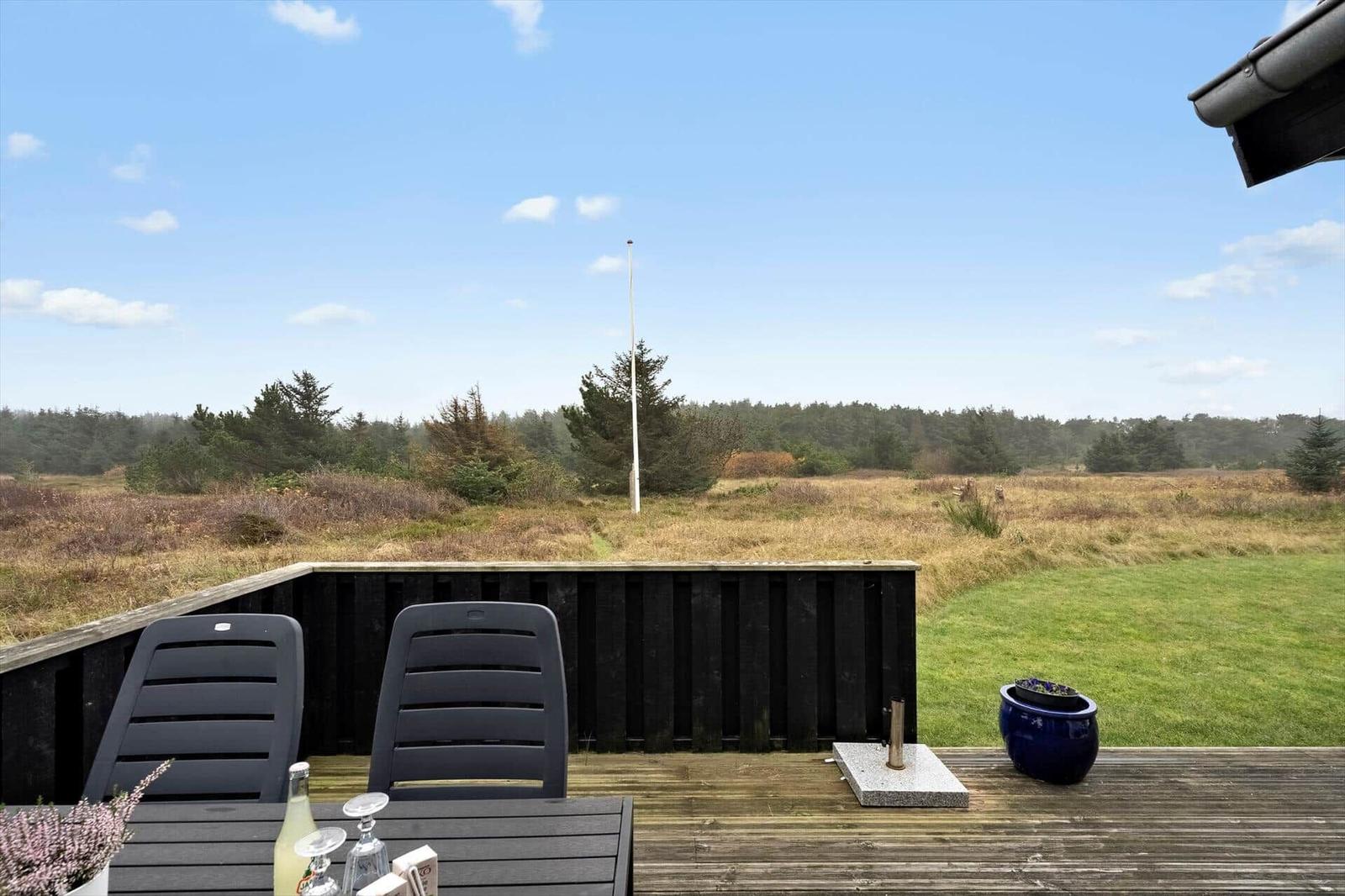 Terrasse mit Tisch, Stühlen und Blick auf Wiese und Wald.