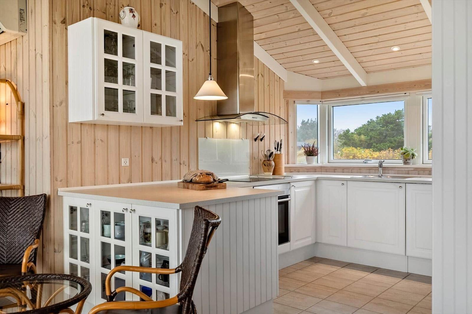Küche mit weißem Schrank und Holzwand, Fenster mit Blick auf Grün