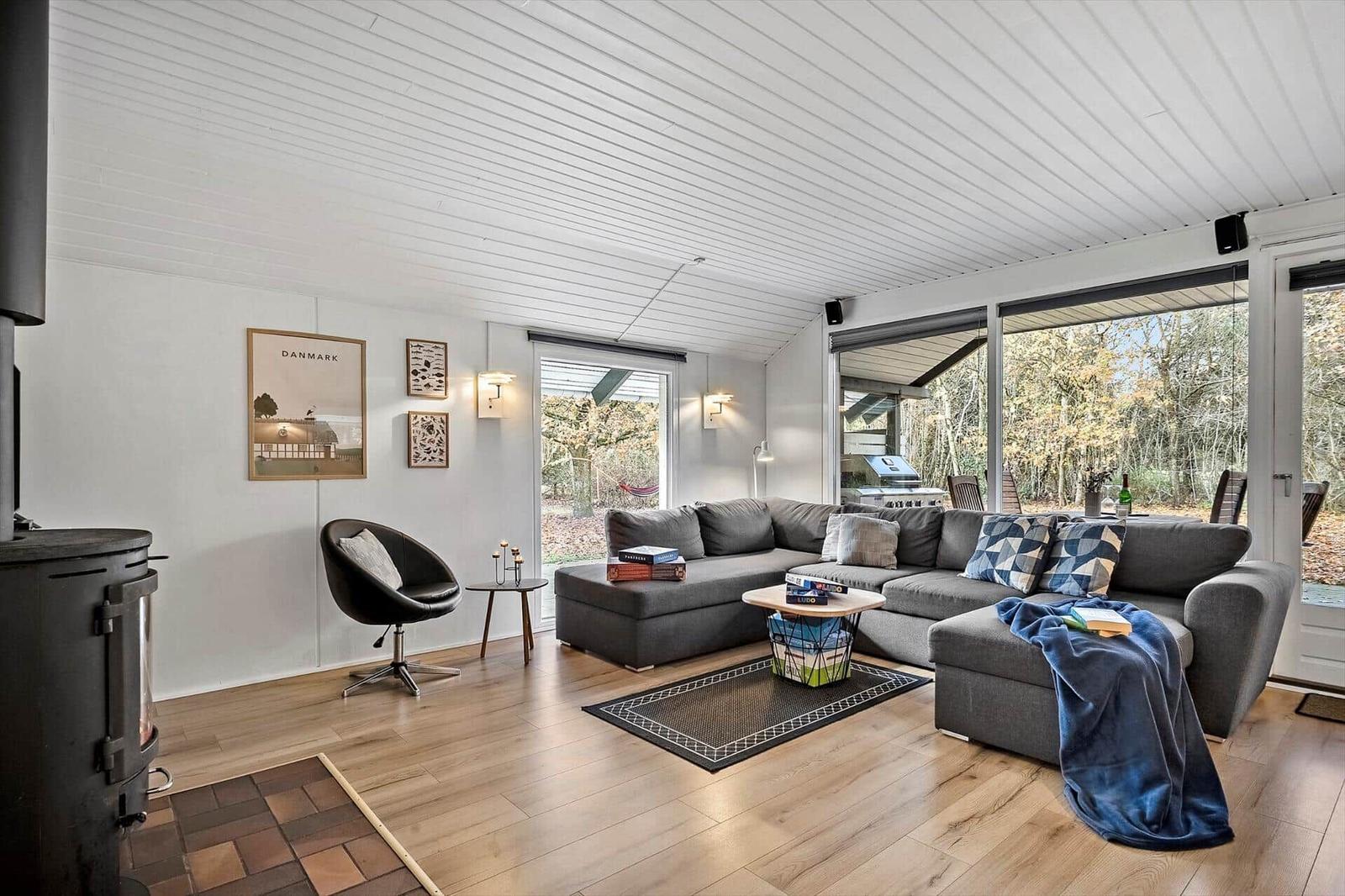Wohnzimmer mit grauem Sofa, Holzboden und Blick auf Garten.