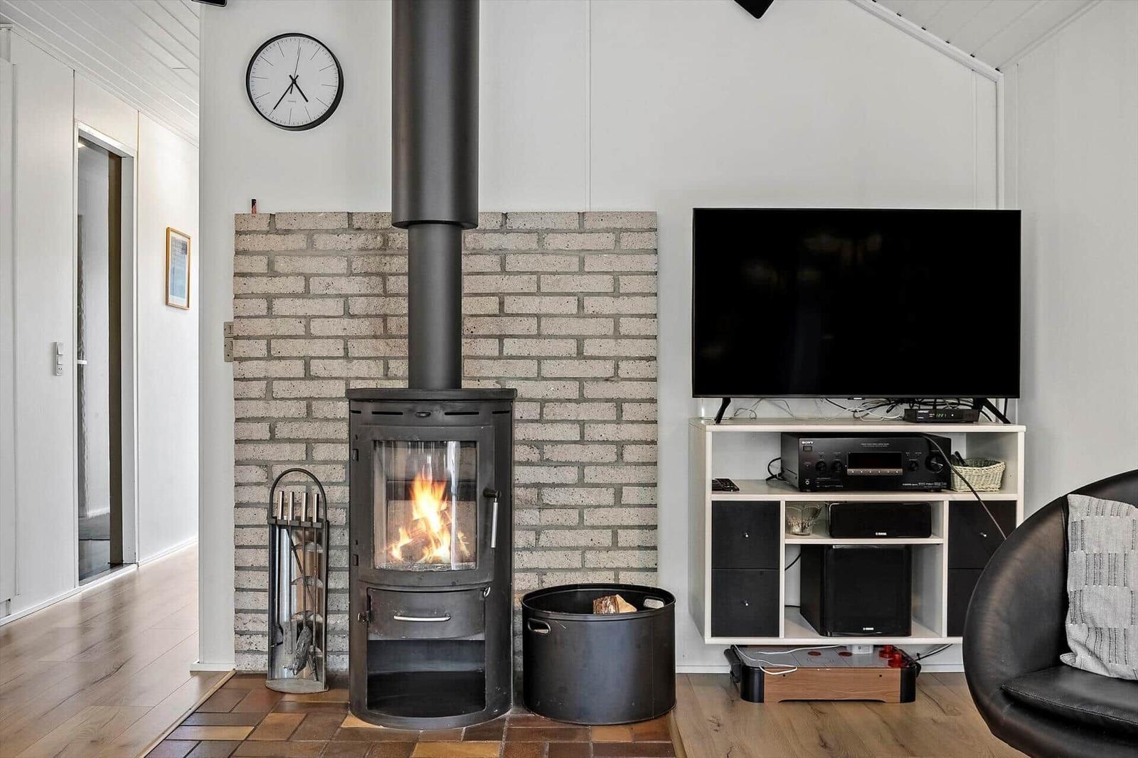 Wohnzimmer mit Kamin, Fernseher und Sitzgelegenheit.