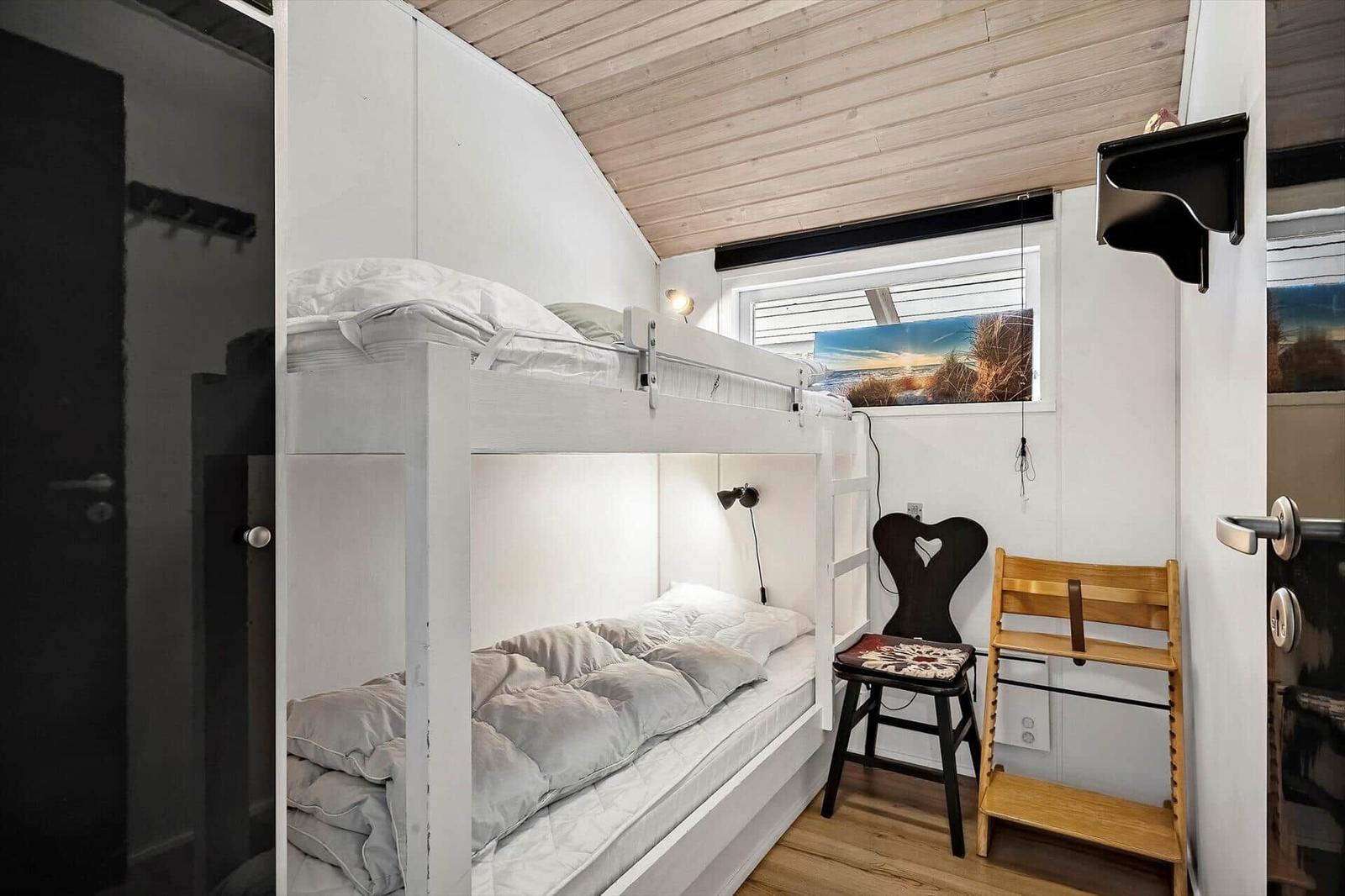 Zimmer mit Doppelstockbett, Stuhl und Fenster mit Blick.