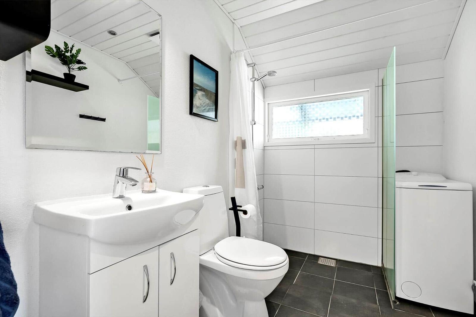 Badezimmer mit Waschbecken, Toilette, Dusche und Fenster.
