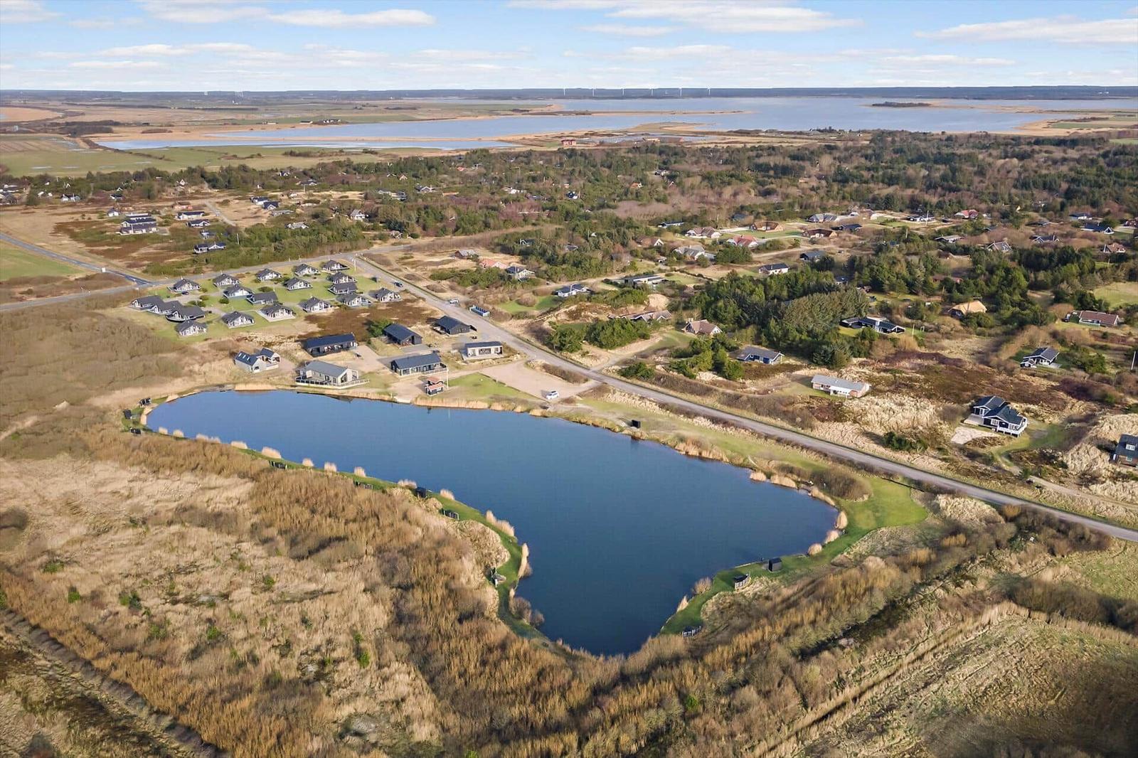 Luftbild einer Wohngegend mit See und Ferienhäusern. Hintergrund: Wasser und Wald.