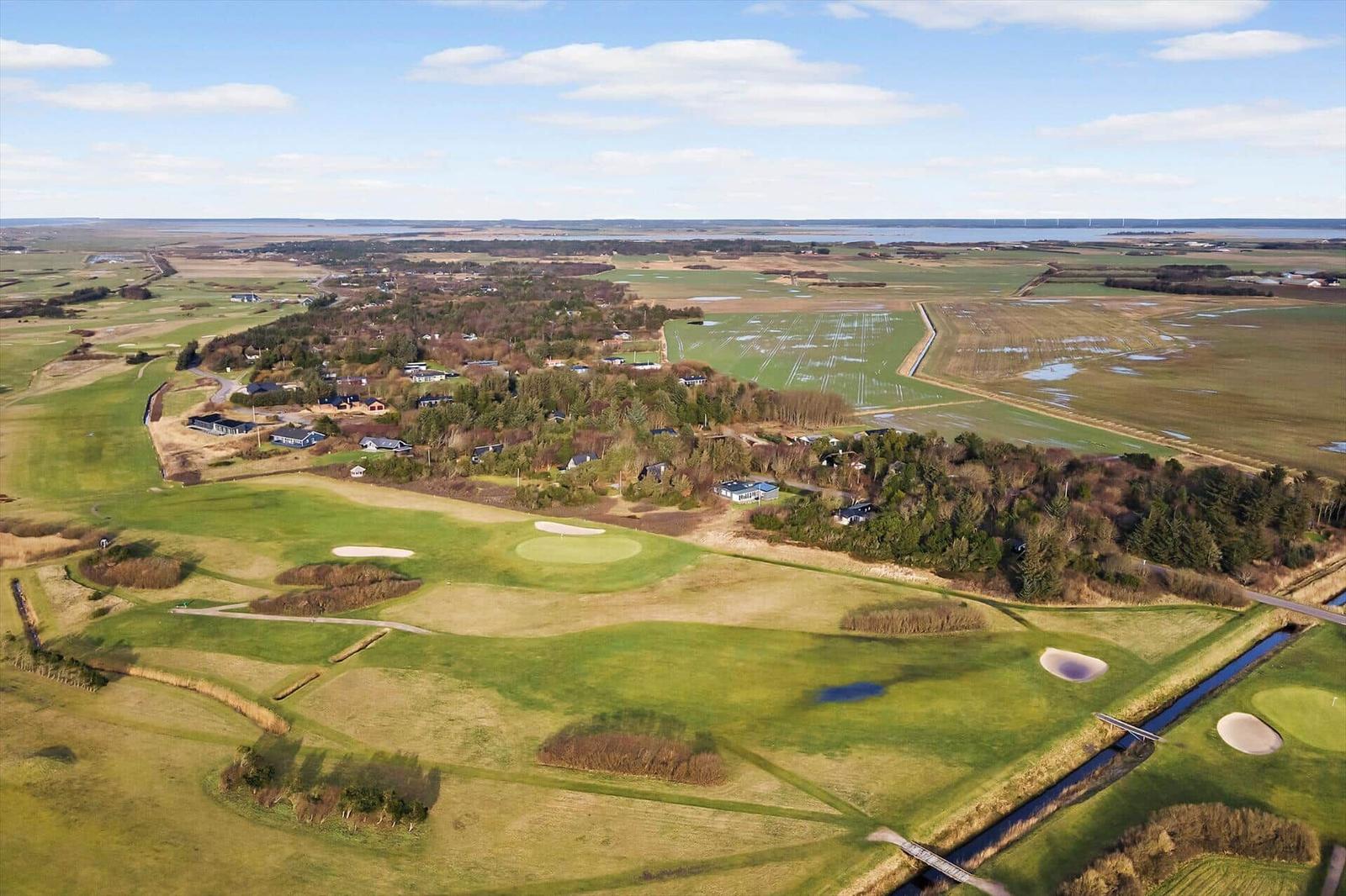 Luftbild eines Golfplatzes mit umliegenden Wiesen und Waldgebieten.