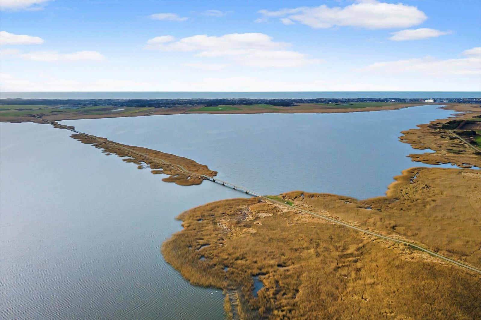 Aerielansicht eines Sees mit Brücke und Uferbereichen.