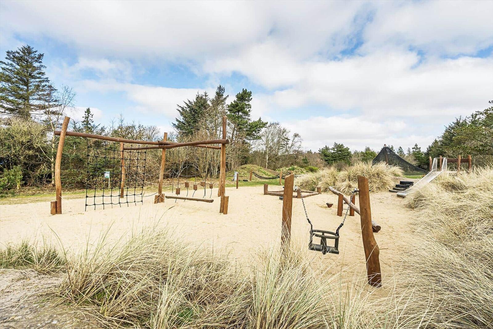 Spielplatz mit Schaukel und Rutsche auf sandigem Gelände