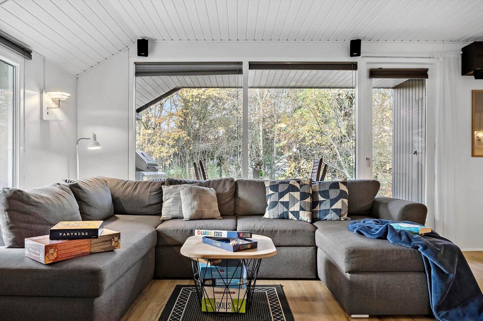 Großer Wohnbereich mit Ecksofa, Tisch und Blick auf den Garten.