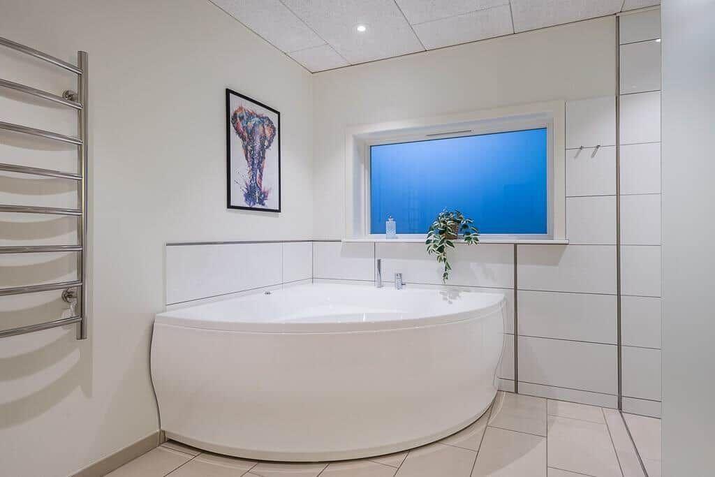 Bathroom with round bathtub, window, and heater.