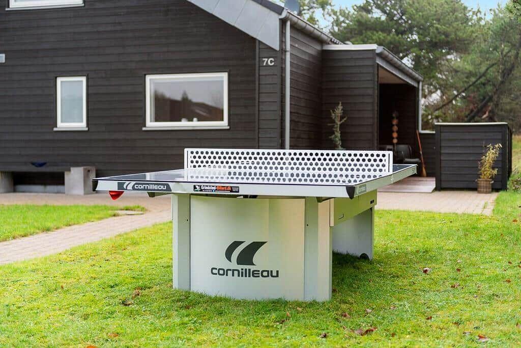 Ping pong table in the garden in front of a house with dark cladding.