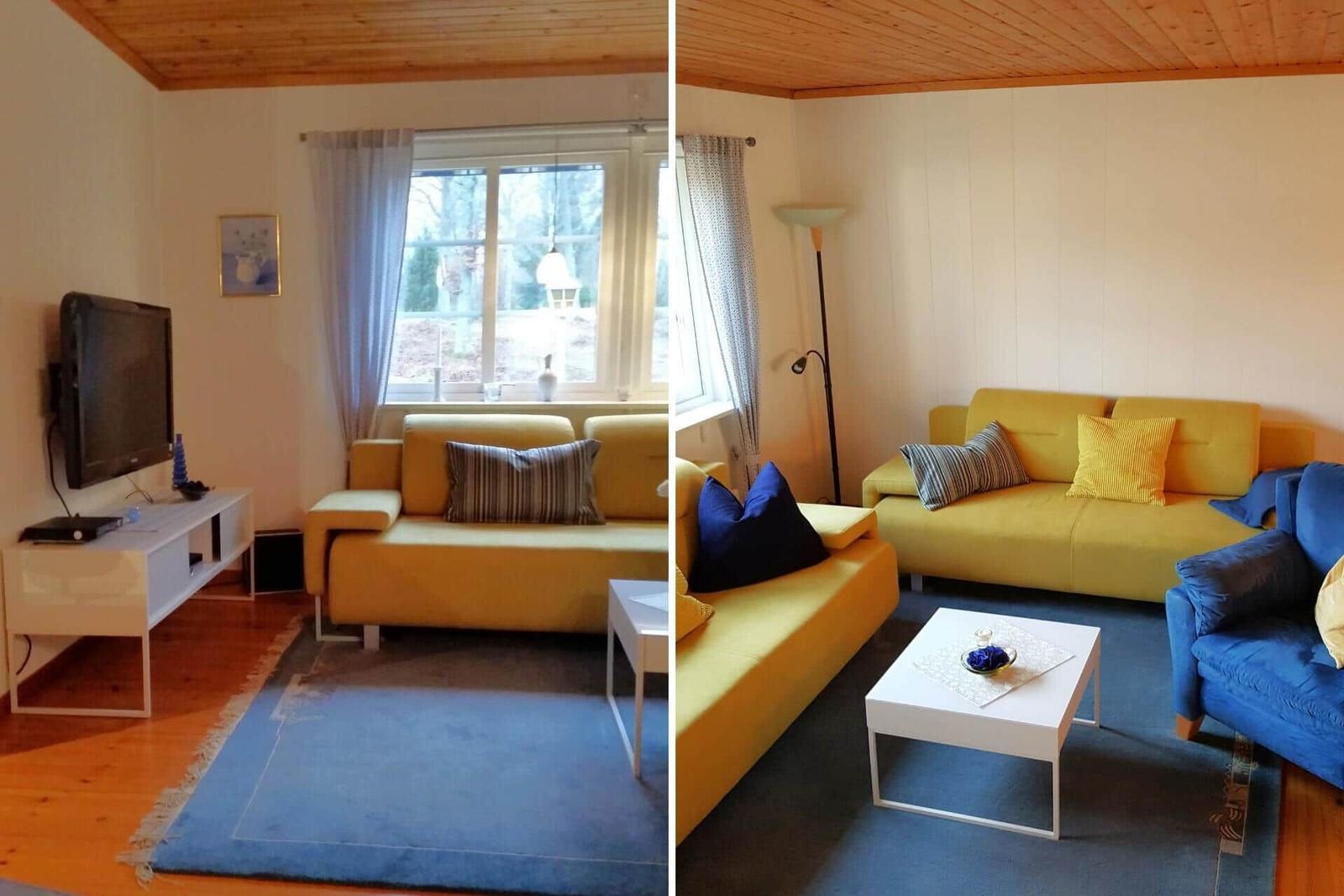 Wohnzimmer mit gelbem Sofa, blauem Teppich und Fernseher an der Wand.