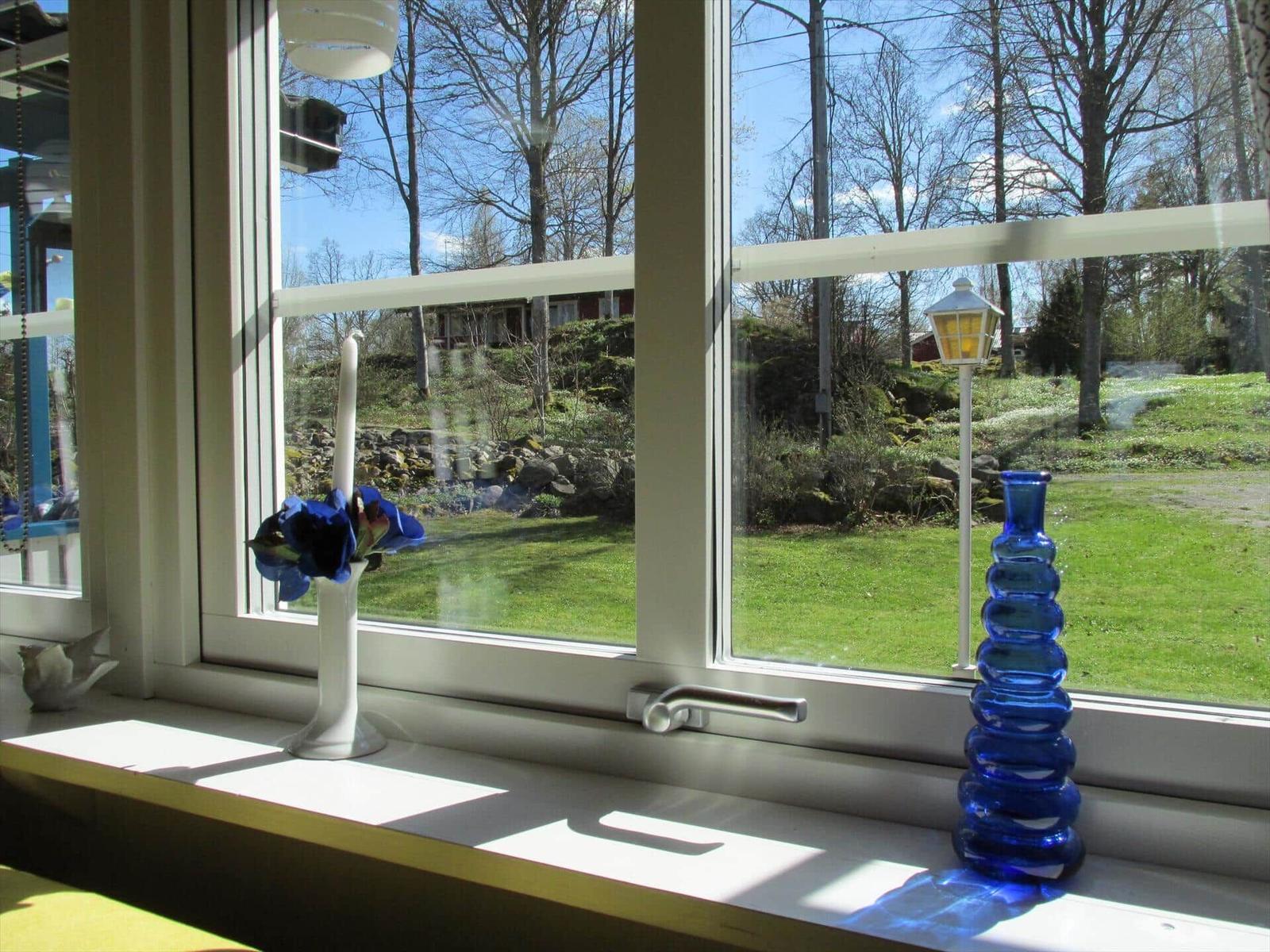 Fensterblick auf grünen Garten mit Laterne und blauem Glasvasen